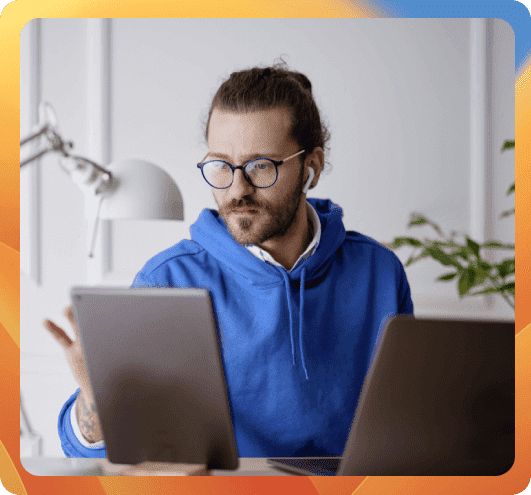 man with glasses working on mac and ipad